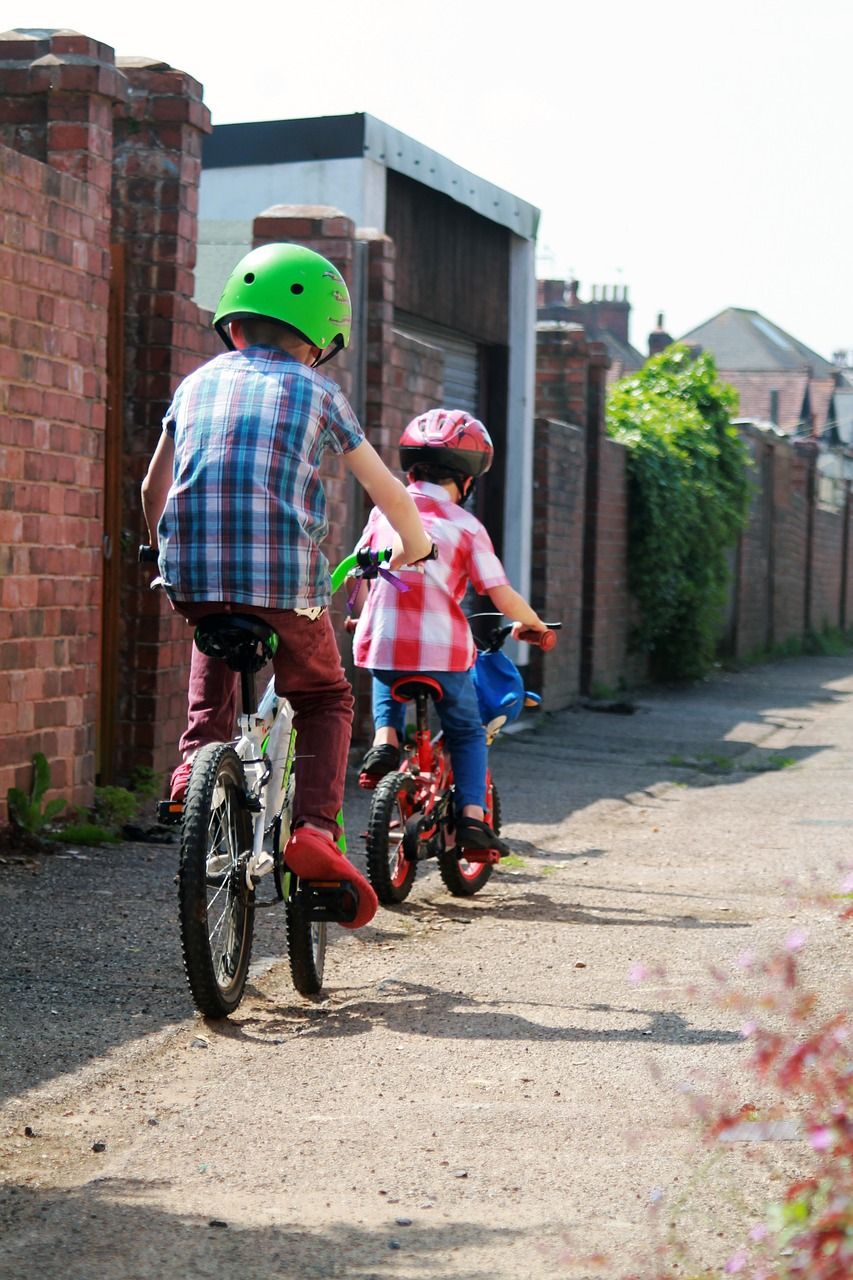 Two kids riding bikes down an alley way
